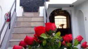 A staircase leading to a door with a window, surrounded by red flowers. - La Casa de Ana (Arequipa)