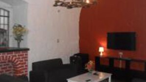 A living room with a fireplace, a television mounted on the wall, and a chandelier. - La Casa de Ana (Arequipa)