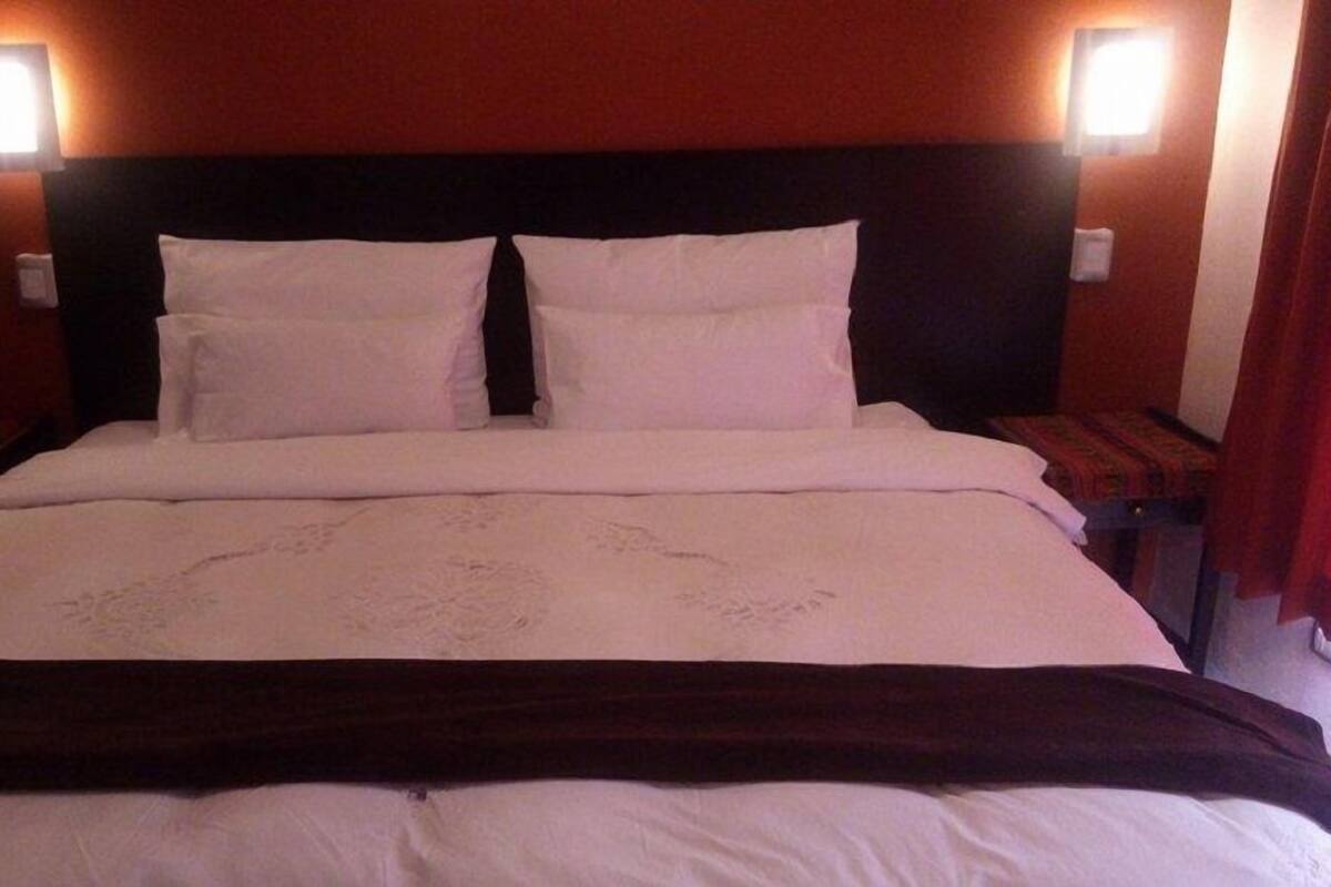 Una habitación de hotel con una cama grande, dos mesitas de noche y dos lámparas de pared.