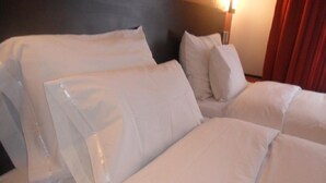 A neatly made bed with white linens and pillows, a headboard, and a wall-mounted light fixture. - La Casa de Ana (Arequipa)