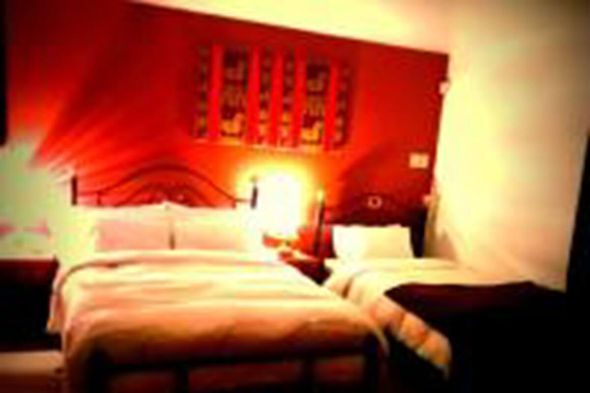 Una habitación de hotel con dos camas, una mesita de noche y una lámpara de pared.