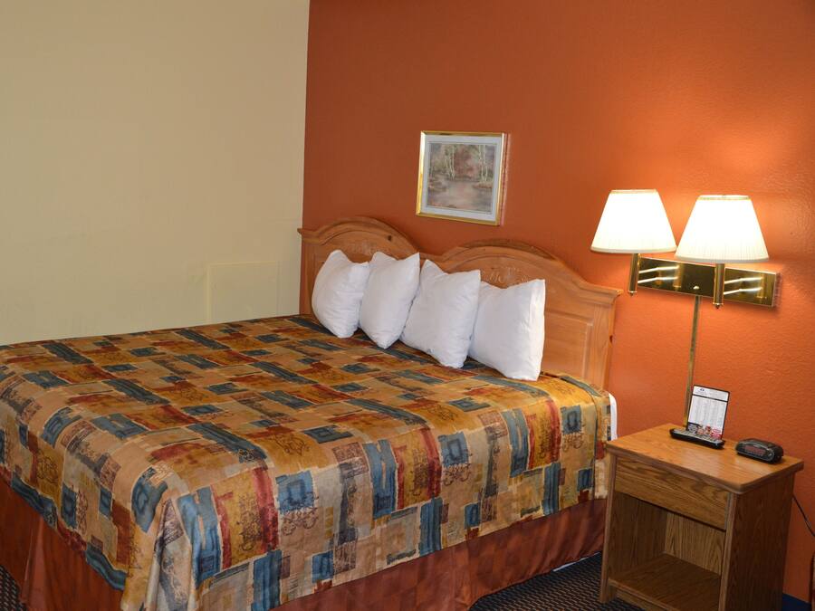 A hotel room with a bed, a nightstand with a lamp, and a painting on the wall.