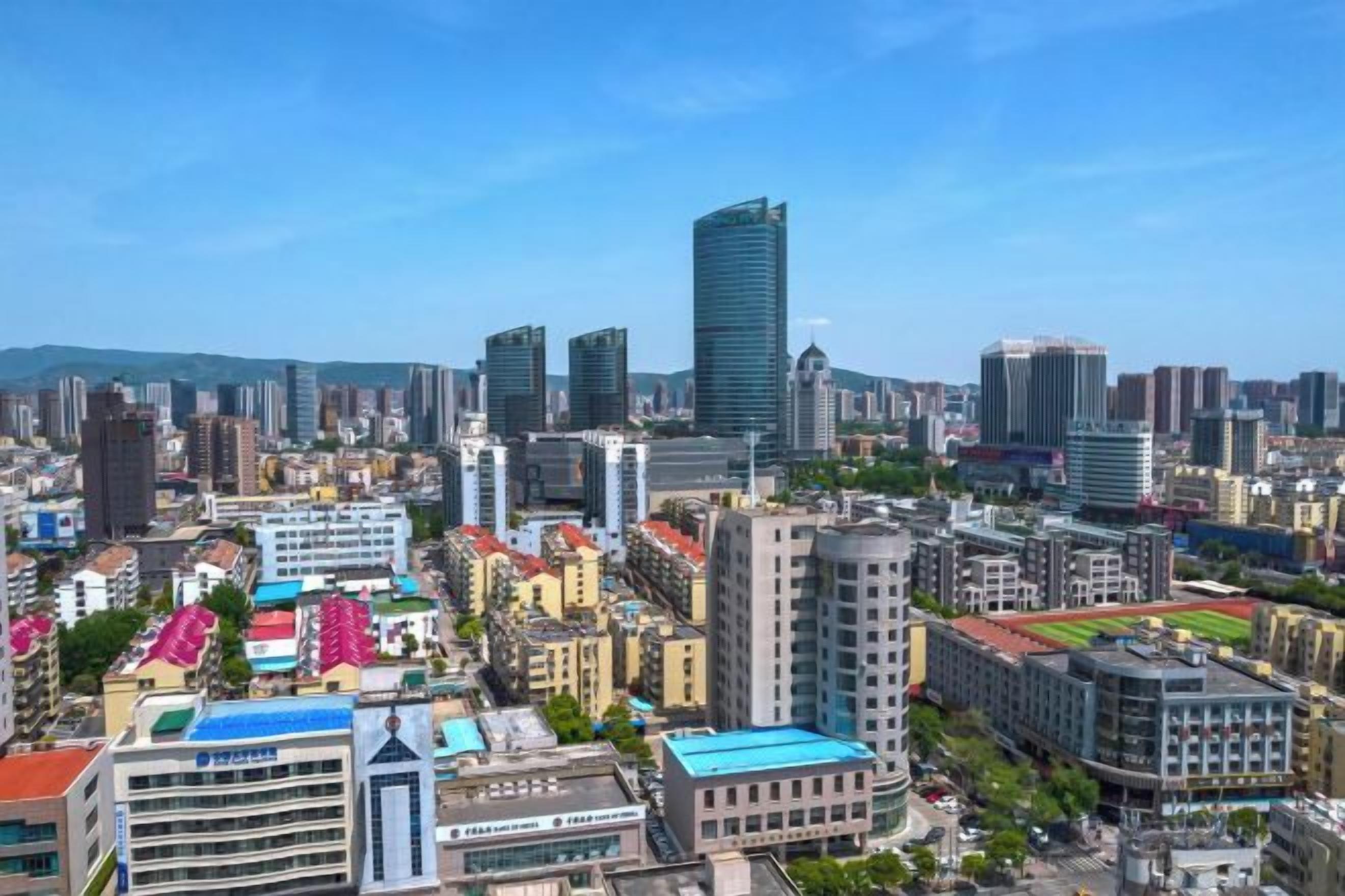 A cityscape with high-rise buildings, a mix of modern and older architecture, and a clear sky.