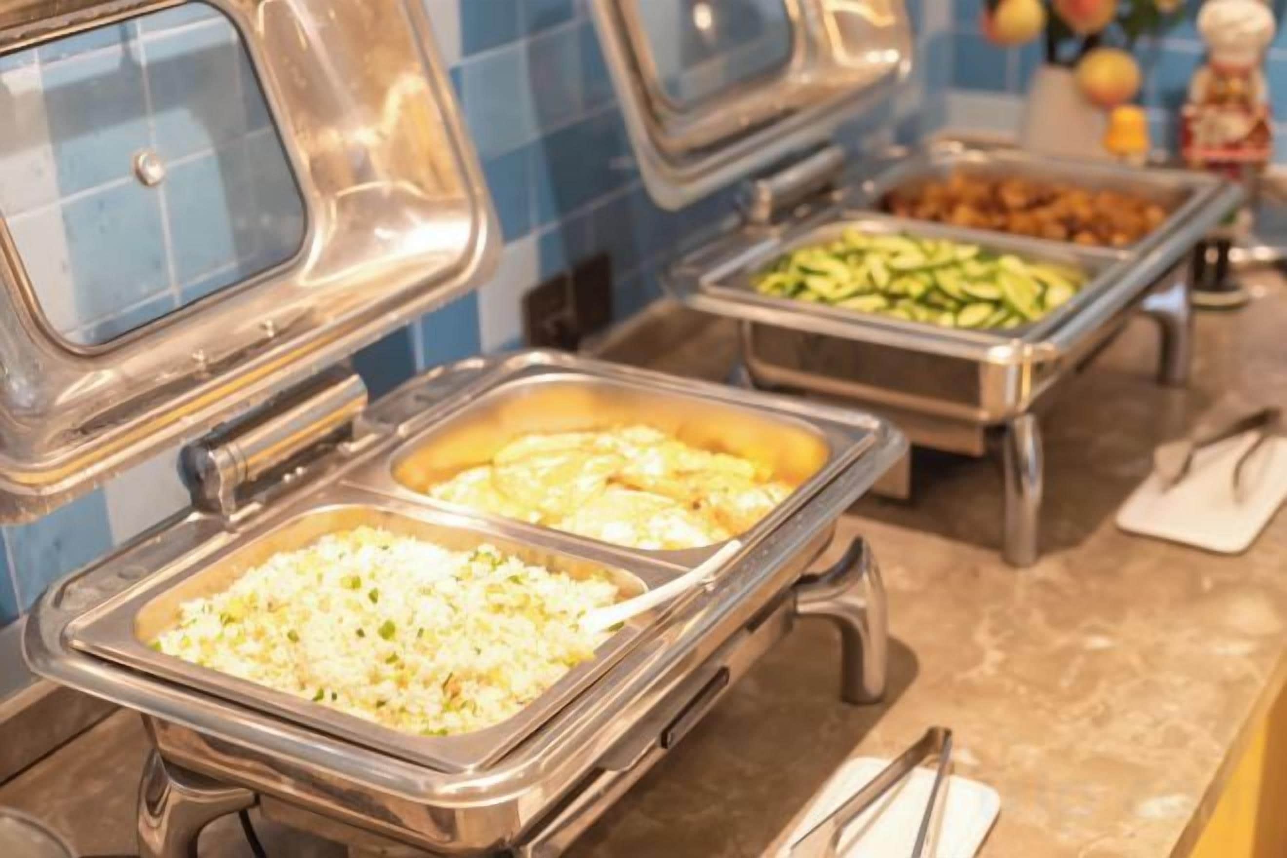 A buffet with various food options including rice, vegetables, and meat dishes.