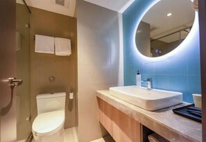Un baño moderno con inodoro, lavamanos y espejo.