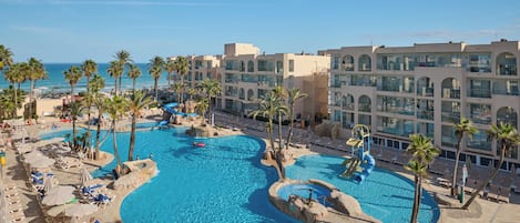 A resort with multiple swimming pools, palm trees, and a beach area.
