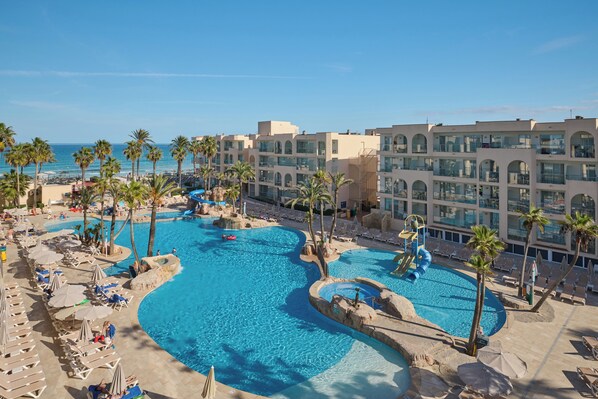 A resort with multiple swimming pools, palm trees, and a beach area. - Grupotel Alcudia Pins (Muro)