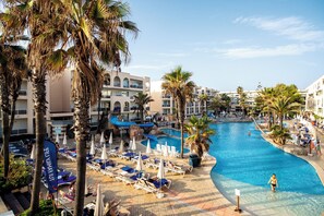 A resort pool area with lounge chairs, umbrellas, and palm trees. - Grupotel Alcudia Pins (Muro)