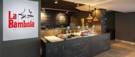 A restaurant interior with a black counter, menu boards, and hanging pendant lights.