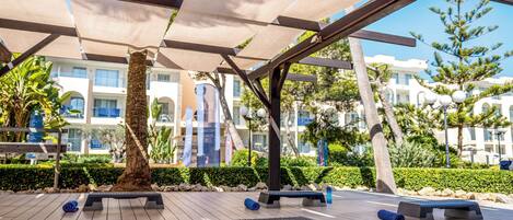 An outdoor exercise area with wooden flooring, exercise equipment, and a tree.