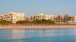 A beachfront hotel with multiple buildings, a sandy beach, and palm trees. - Grupotel Alcudia Pins (Muro)