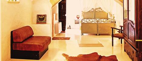 A room with a cowhide rug, a sofa, a bed with a canopy, and a wooden cabinet.