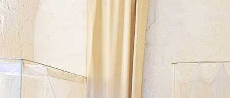 A room with two beds, each with a canopy, and a large curtain dividing the space.