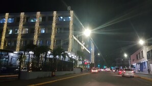 Straße bei Nacht mit Gebäuden an beiden Seiten, Straßenlaternen und Autos.