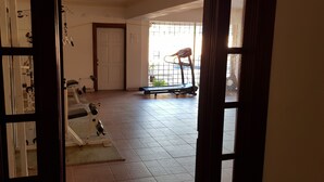 Ett gym inomhus med träningsutrustning, en dörr och ett fönster med utsikt över omgivningen.