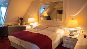 A hotel room with a bed, bedside lamps, a desk, and a mirror.