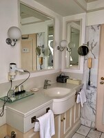 A bathroom with a large mirror, a sink, a hairdryer, and a telephone.