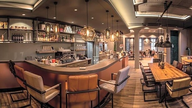 A bar area with a counter, seating, and hanging lights.