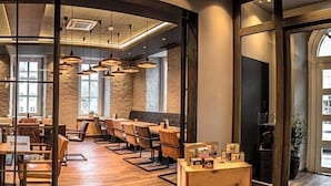 A restaurant with a modern interior, featuring wooden tables and chairs, pendant lighting, and a stone wall backdrop.