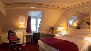 Ein Hotelzimmer mit Bett, Schreibtisch, Stuhl und einem großen Spiegel.