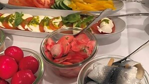 A buffet with various food items including fish, tomatoes, cucumbers, and cheese.