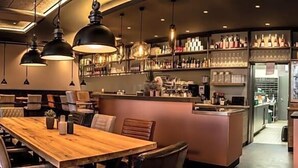 A restaurant with a bar area, seating, and a counter.