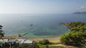 A coastal view with a beach, boats, and a clear sky.