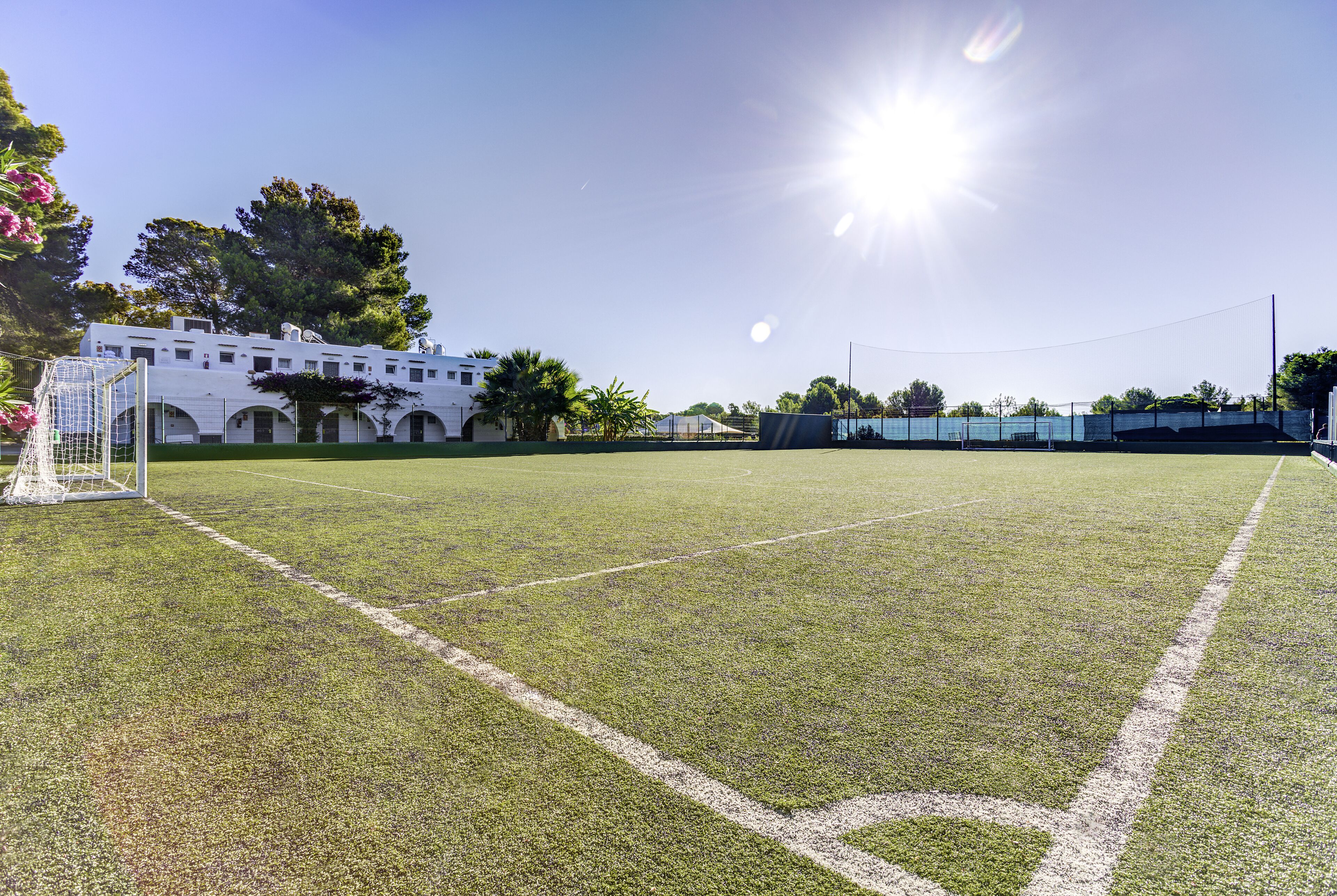 A soccer field with goalposts and a building in the background.