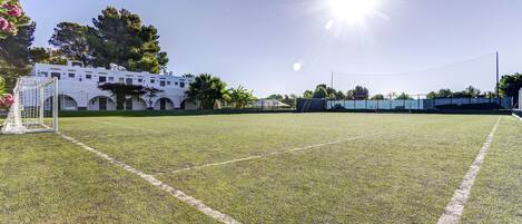 A soccer field with goalposts and a building in the background.