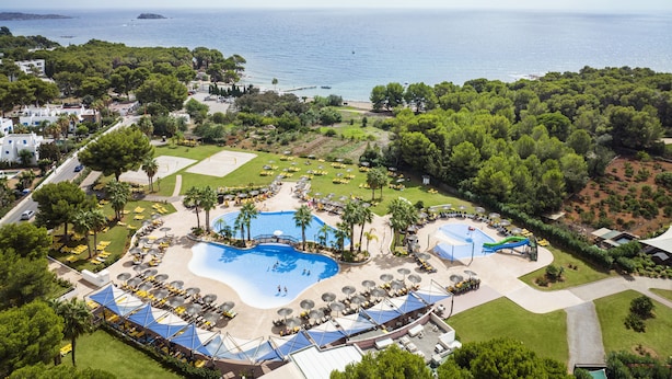 A resort with multiple swimming pools, sun loungers, and a view of the sea.