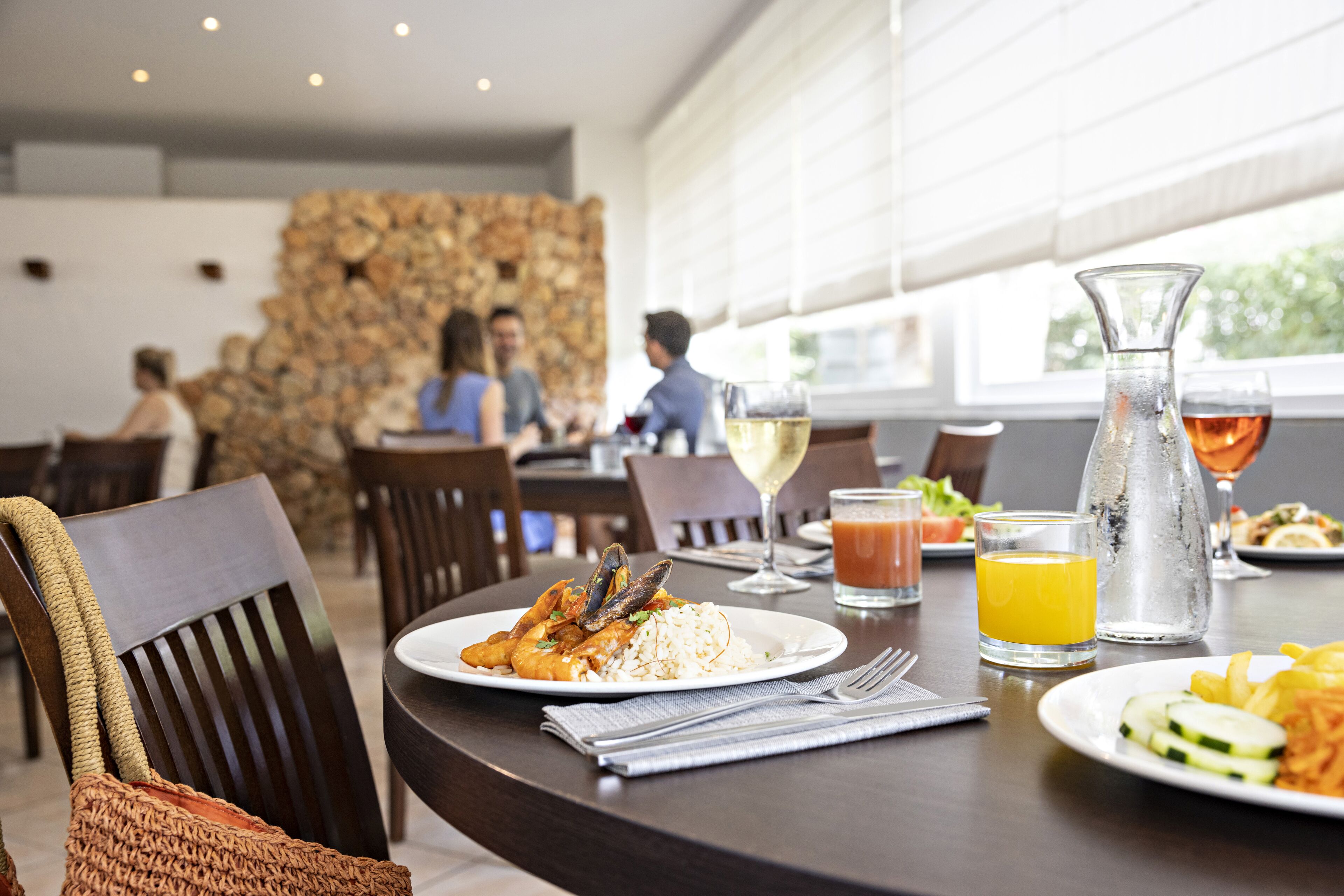 A dining table with a plate of seafood, a pitcher, and glasses of wine and juice.