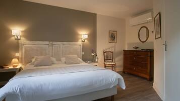 A neatly made bed with white linens, a wooden dresser, and two wall-mounted lamps.
