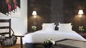 A hotel room with a large bed, two bedside lamps, a laptop on a bedside table, a chair, and a handbag. - Château de Creissels (Creissels)