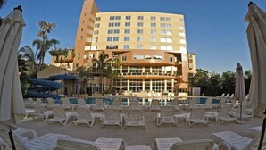 Un hotel con un amplio área de piscina, numerosas tumbonas y sombrillas.