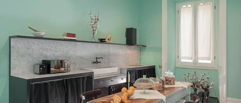 A kitchen with a marble countertop, a sink, and a dining area with a wooden table and chairs.