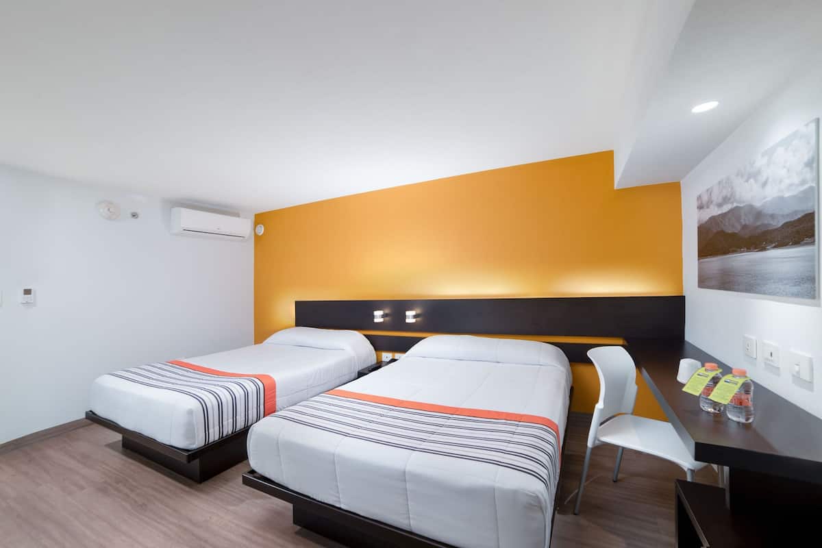 A hotel room with two beds, a desk, and a chair.