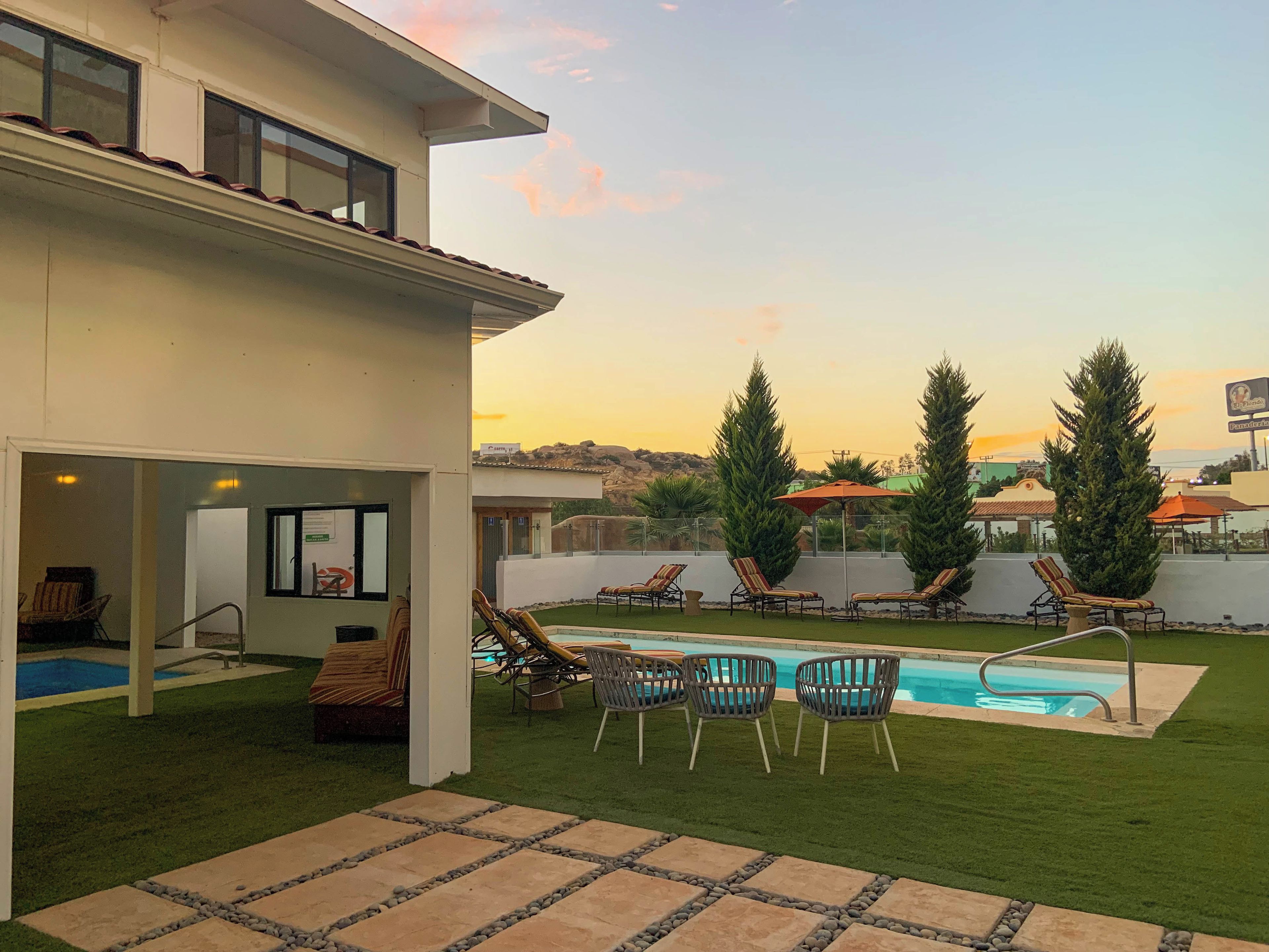 A modern house with a swimming pool, outdoor seating, and a view of the landscape.