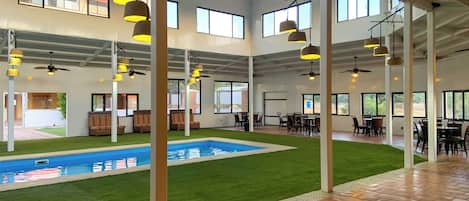 Un vaste espace intérieur doté d’une piscine, de plusieurs coins salon et de grandes fenêtres.