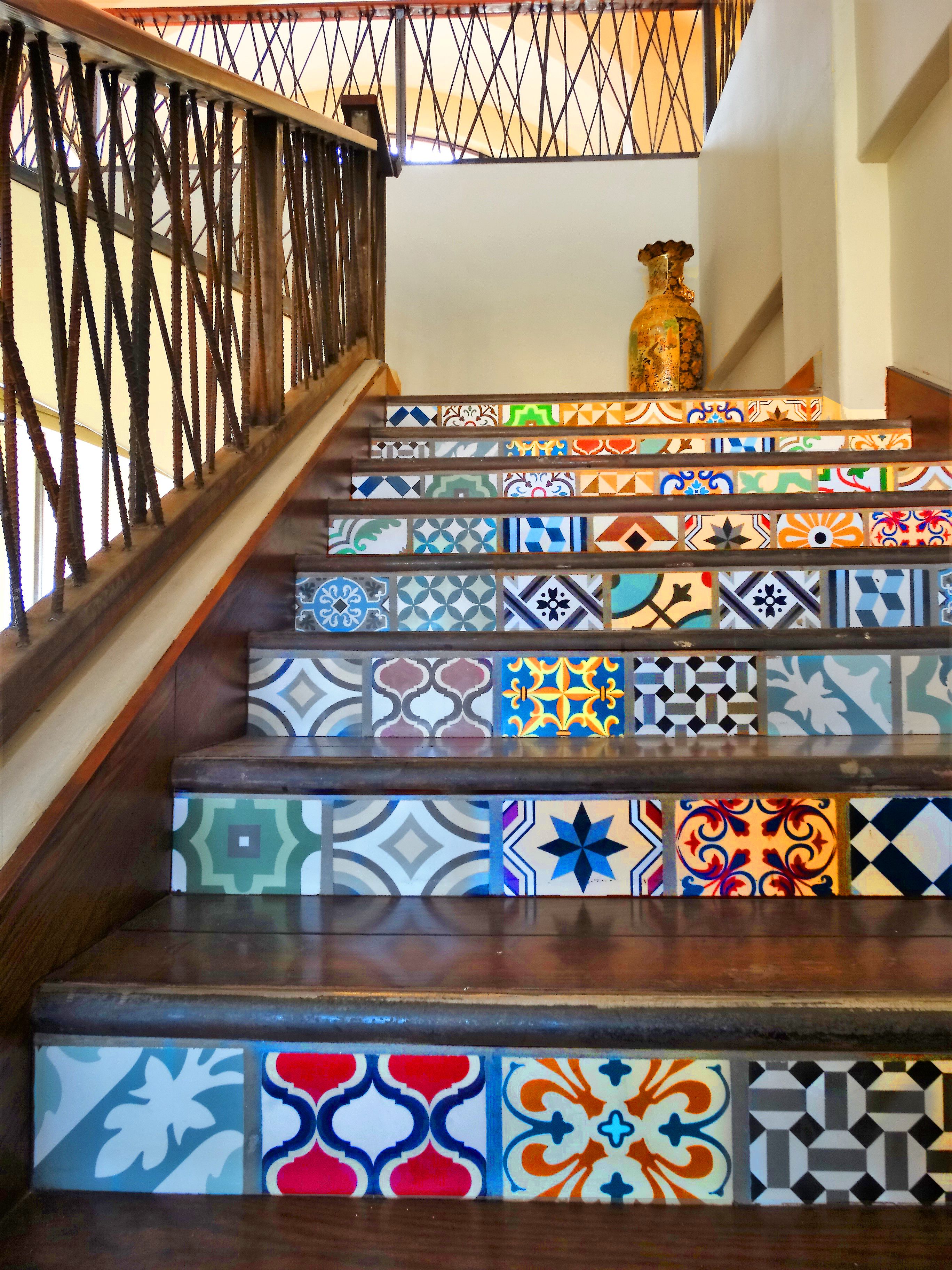 A staircase with colorful, patterned tiles and a wooden railing.
