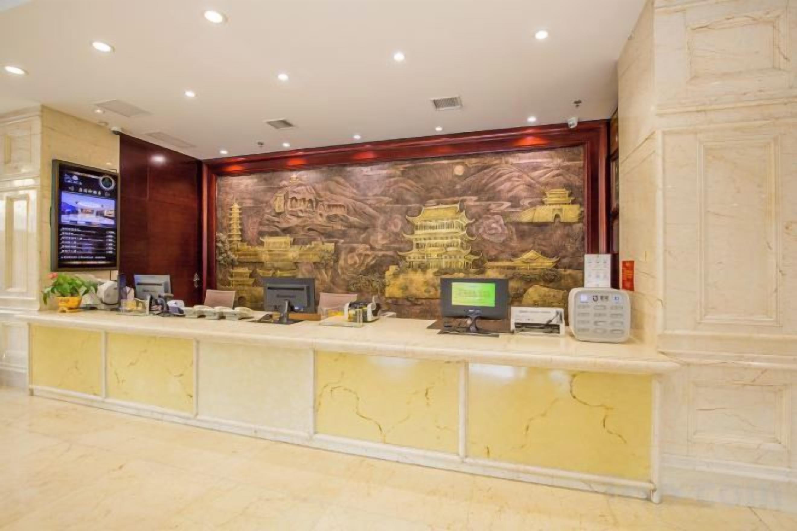 A hotel reception desk with a digital display, a computer, and a telephone.