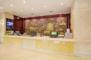 Un mostrador de recepción de hotel con pantalla digital, computadora y teléfono.