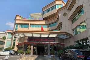 A multi-story hotel with a prominent entrance, a covered area, and a parking lot. - Ganzhou Hotel (Ganzhou)