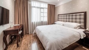 Una habitación de hotel con una cama grande, un escritorio, una silla, un televisor y una ventana con cortinas.