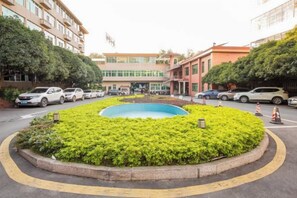 A roundabout with a central landscaped area, surrounded by multi-story buildings, and parked cars along the roadside. - Ganzhou Hotel (Ganzhou)