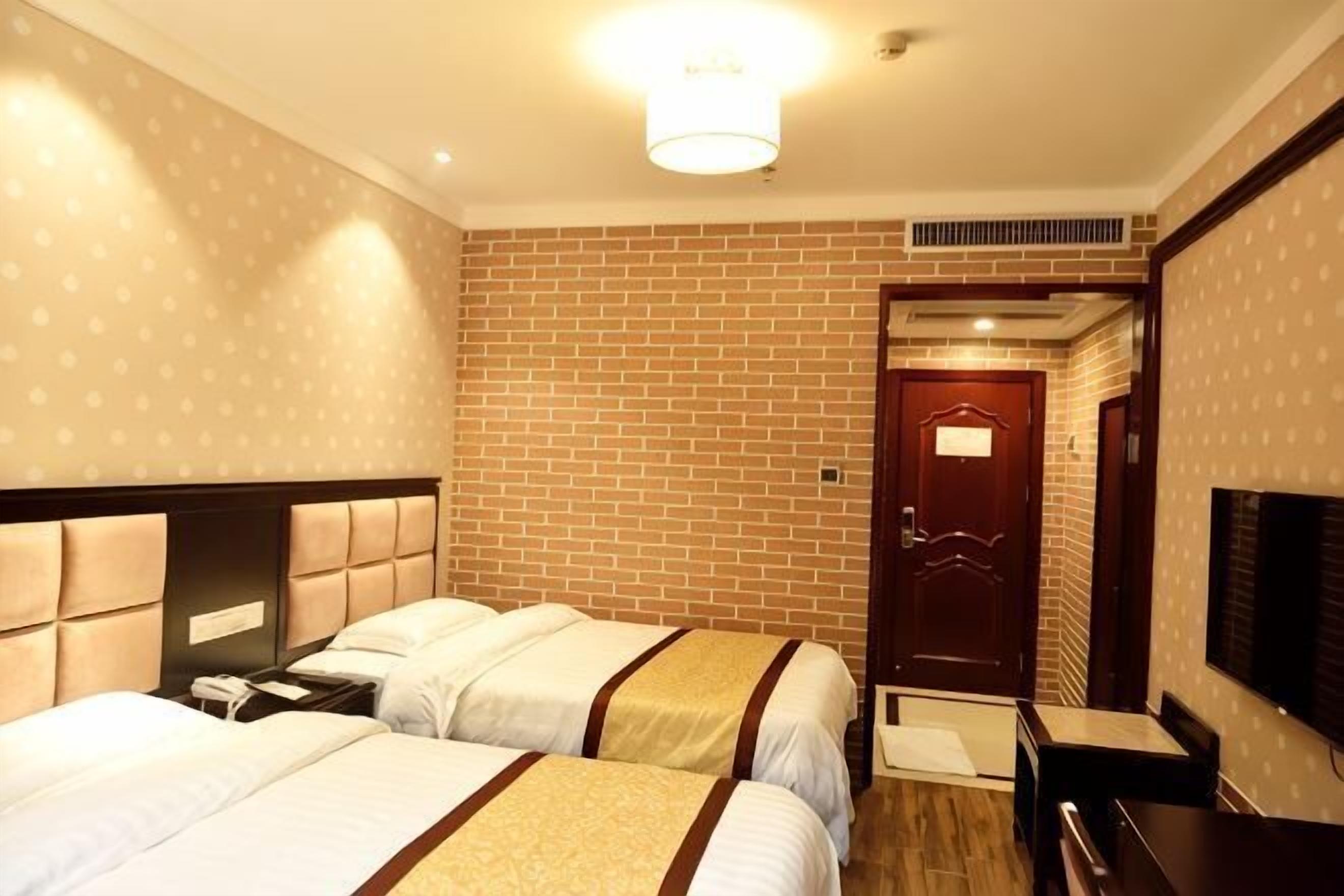 A hotel room with two beds, a TV, a desk, and a door leading to the bathroom.