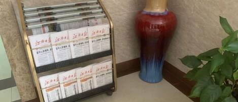 Una zona de recepción con un atril metálico informativo y un jarrón decorativo.