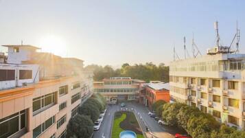 Un edificio de varios pisos con un patio central, rodeado de árboles y una piscina.