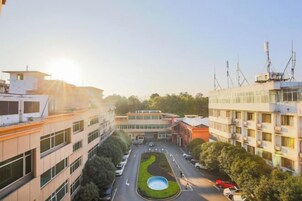 Un edificio de varios pisos con un patio central, rodeado de árboles y una piscina.