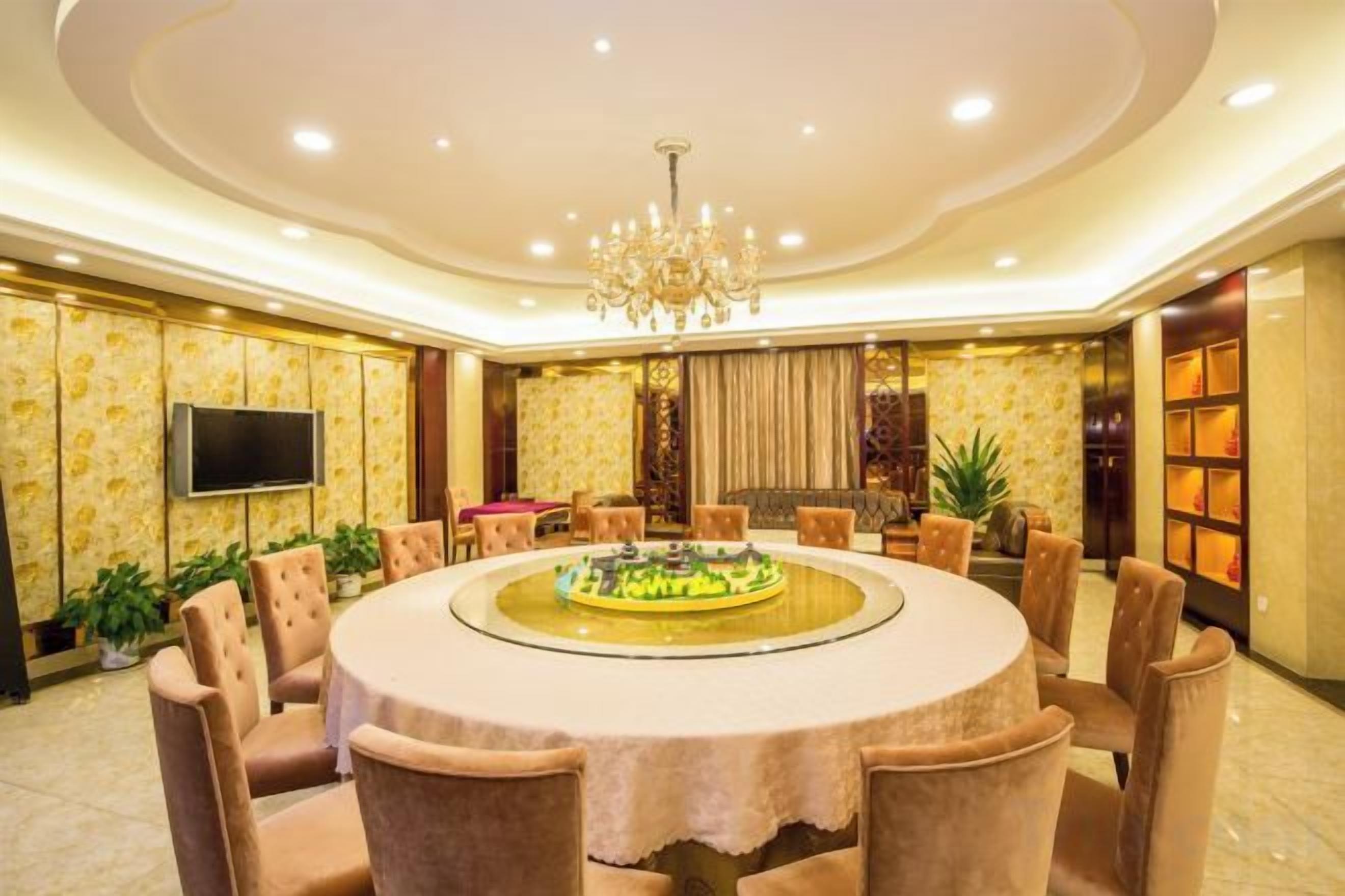 Una mesa de comedor redonda con sillas, un candelabro y un televisor de pantalla plana en la pared.