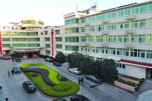 A multi-story building with a central courtyard, parking area, and a red vertical feature. - Ganzhou Hotel (Ganzhou)